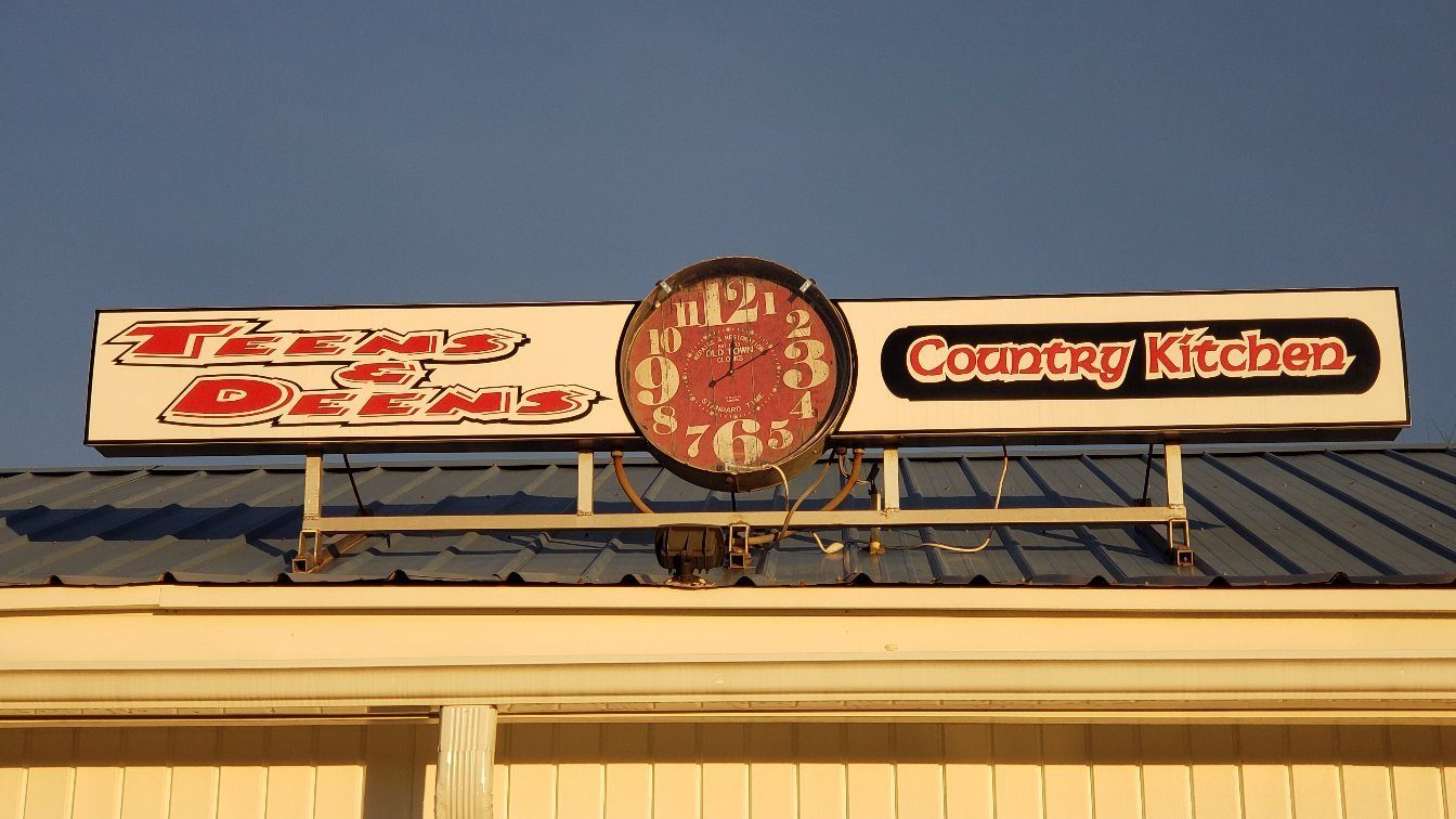 The Teens & Deens Country Kitchen roof sign with its red clock and Country Kitchen panel